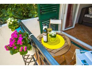 a table with a bottle of wine and flowers on a balcony at Apartments Cambi in Kaštela