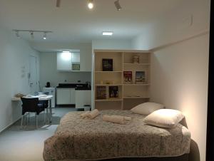 a bedroom with a large bed and a kitchen at Studio 811 in Marília