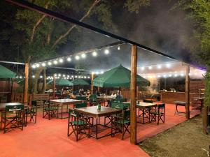 - un restaurant avec des tables et des parasols verts la nuit dans l'établissement Wicz Apart Iguazú, à Puerto Iguazú