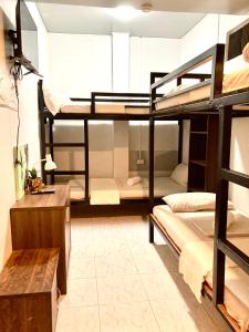 a room with three bunk beds and a desk at Barrio House Mactan in Mactan