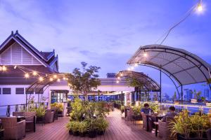 un patio al aire libre con mesas, sillas y luces en Ohana Phnom Penh Palace Hotel en Phnom Penh