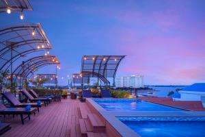 a hotel rooftop with a pool and a view of the city at Ohana Phnom Penh Palace Hotel in Phnom Penh