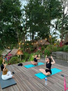 un grupo de personas haciendo yoga en una terraza de madera en Taman Asta Gangga by ecommerceloka, en Silebeng