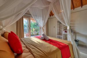 sypialnia z łóżkiem z baldachimem i czerwonymi poduszkami w obiekcie Cassava Penida Cottage w mieście Nusa Penida