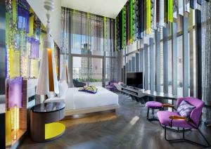 a hotel room with a bed and chairs and a tv at W Kuala Lumpur Hotel in Kuala Lumpur