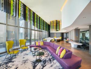 a living room with a purple couch and yellow chairs at W Kuala Lumpur Hotel in Kuala Lumpur