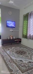 um quarto com um tapete e uma televisão na parede em FIZWAN HOMESTAY em Kuantan