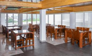 a dining room with tables and chairs and windows at JL Grand Hotel in Nuwara Eliya
