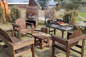 a group of wooden chairs and a grill with a grill at Retiro San Francisco 2 hasta 6 huespedes -Pais Uruguay in Paysandú