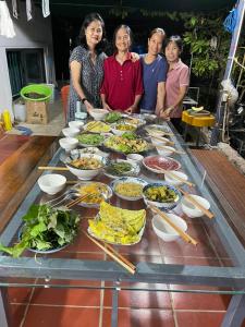 Đức Lưu Quang Hotel Bình Thuận في Tuy Phong: مجموعة نساء واقفات حول طاولة مليئة بالطعام