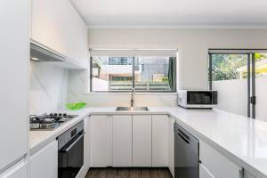 a white kitchen with a sink and a microwave at DY008 - 3 bedroom townhouse - Dee Why in Sydney