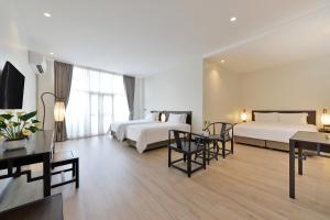 a hotel room with two beds and a table and chairs at Oldthaiheng Hotel in Bangkok