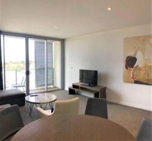 a living room with a tv and a table and chairs at Serain Residences on 88 Archer Chatswood in Sydney