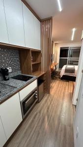 a kitchen with white cabinets and a room with a bed at Moov 2415 Studio Mooca in Sao Paulo