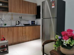 uma cozinha com um frigorífico e um vaso de rosas em klia alanis residence free wifi em Sepang