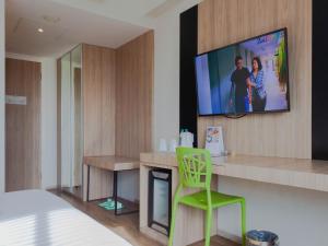 ジンバランにあるZuri Express Jimbaranの壁にテレビと緑の椅子が備わる客室です。