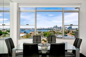 a dining room with a table and chairs and a large window at HARIS - Modern 2BR Apartment with Views in Sydney