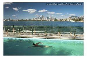 a person swimming in a pool with a city in the background at HARIS - Modern 2BR Apartment with Views in Sydney