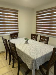 a dining room with a table and chairs and windows at Cómoda y amplía casa con Quincho in Punta Arenas