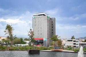 a tall building with a fountain in front of it at Holiday Inn Express Mexico City Satelite by IHG in Mexico City