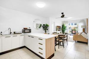 a kitchen with white cabinets and a dining room at Tropical Terraces in Cairns