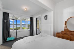 a white bedroom with a large bed and a mirror at The Middle in Rotoiti