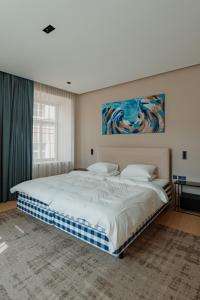 a bedroom with a large bed with a painting on the wall at Royal Marbles in Vilnius