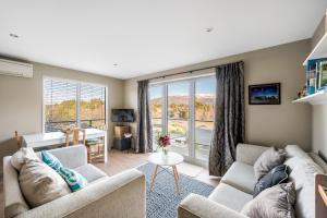 a living room with two couches and a large window at Criffel Garden Apartment in Wanaka
