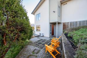 dos bancos de madera sentados en una pasarela frente a una casa en Criffel Garden Apartment, en Wanaka