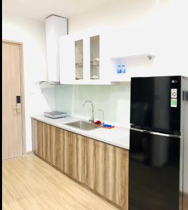 La cuisine est équipée d'un réfrigérateur noir et d'un évier. dans l'établissement Studio Luxury Sakura - Vinhome Smart city Mỹ Đình, à Hanoï