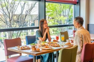 a man and a woman sitting at a table with food at Hotel Nikko Kanazawa in Kanazawa