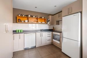 a kitchen with white cabinets and a white refrigerator at Criffel Garden Apartment in Wanaka