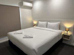 a bedroom with a large white bed with two towels on it at Golf View Motel in Sanctuary Point