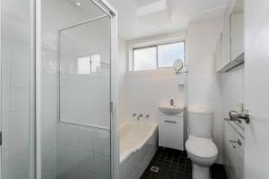 a white bathroom with a toilet and a shower at CRE31 - renovated 1 bedroom unit - Cremorne in Sydney