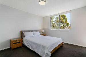 a white bedroom with a bed and a window at CRE31 - renovated 1 bedroom unit - Cremorne in Sydney