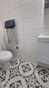 a bathroom with a toilet and a black and white rug at Cambridge Suites in Harmondsworth