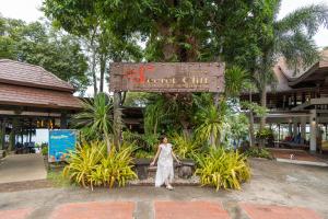 uma mulher em pé em frente a uma placa de resort em Secret Cliff Resort & Restaurant - SHA Plus em Praia de Karon