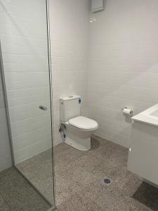 a bathroom with a toilet and a glass shower at Golf View Motel in Sanctuary Point
