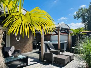 een patio met een tuinhuisje, stoelen en een tafel bij Vakantiehuis de Heide in Bergen op Zoom