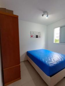 um quarto com uma cama azul e uma cômoda em Apartamento Jardim das Palmeiras II - Ubatuba em Ubatuba