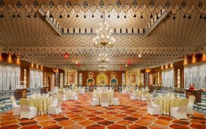 un salón de banquetes con mesas y sillas blancas y una lámpara de araña en Noormahal Palace Hotel, en Karnal