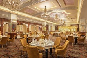 a dining room with tables and chairs and chandeliers at Noormahal Palace Hotel in Karnāl