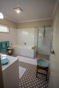 a bathroom with a shower and a tub and a chair at Meander Retreat - The Green Room in Springton