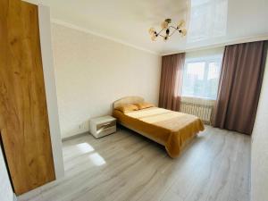 1 dormitorio con cama y ventana en 2.х полноценная . ЖК комфорт., en Kokshetau