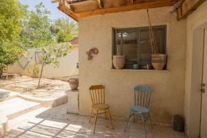 dos sillas sentadas fuera de una casa con ventana en Desert Pearl en Beer Sheva