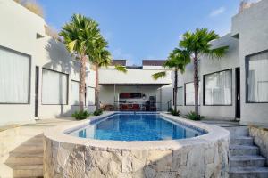 een zwembad voor een huis met palmbomen bij KAYA Uluwatu in Uluwatu