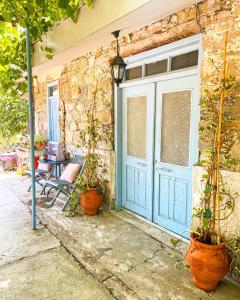Holiday House Prodromos في برودروموس: الباب الأزرق لبيت به نباتات الفخار
