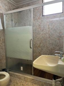 uma casa de banho com uma cabina de duche em vidro com um lavatório e um WC. em CHINA STAR HOTEL em Kolonia