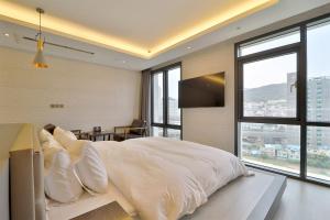 a bedroom with a large bed with white sheets and pillows at HOTEL YUNA Business in Busan