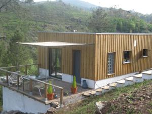ein kleines Holzhaus mit einer Terrasse mit Pflanzen in der Unterkunft Casa Do Pinheiral in Ponte da Barca